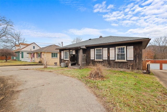 ranch-style home featuring a garage, an outbuilding, central AC, and a front lawn