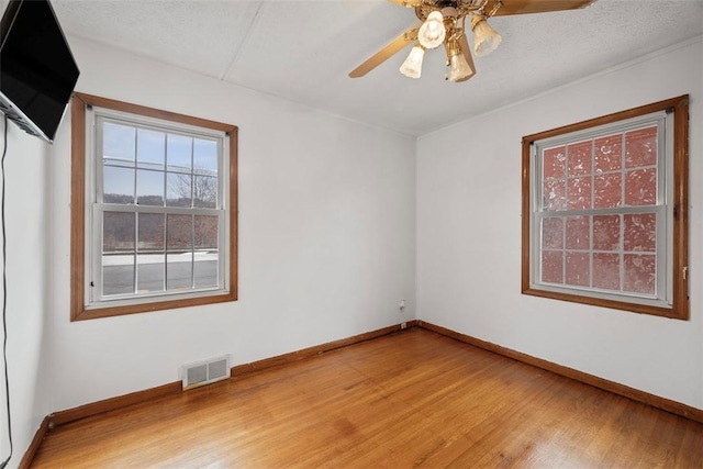 empty room with ceiling fan, hardwood / wood-style floors, and a textured ceiling