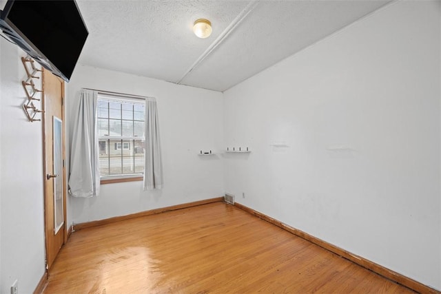 unfurnished room with light hardwood / wood-style floors and a textured ceiling