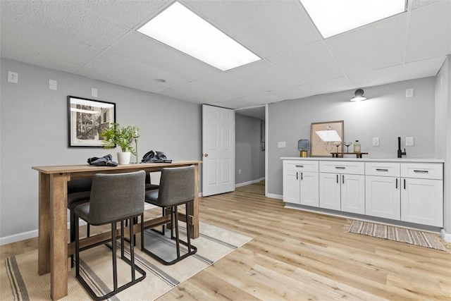 dining space featuring a drop ceiling and light hardwood / wood-style flooring