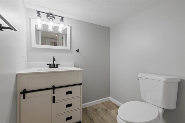 bathroom featuring wood-type flooring, vanity, a textured ceiling, and toilet