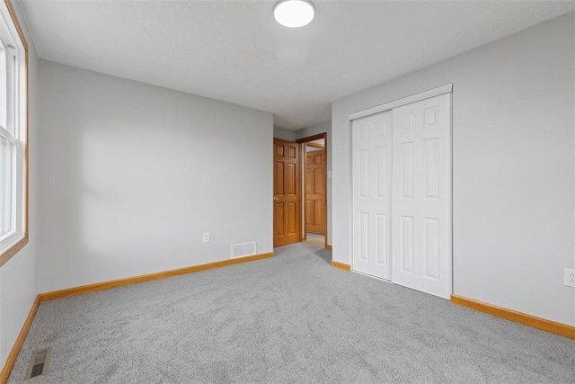 unfurnished bedroom featuring multiple windows, a closet, and carpet