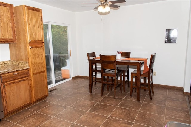 dining space featuring dark tile patterned flooring and ceiling fan