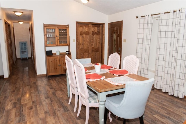 dining area featuring vaulted ceiling and dark hardwood / wood-style floors