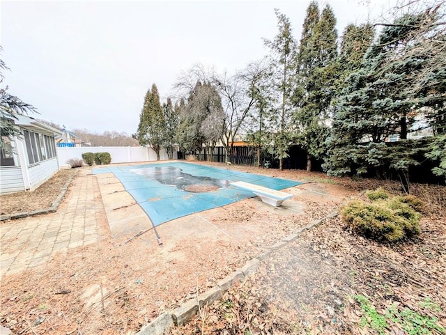 view of swimming pool featuring a patio area and a diving board