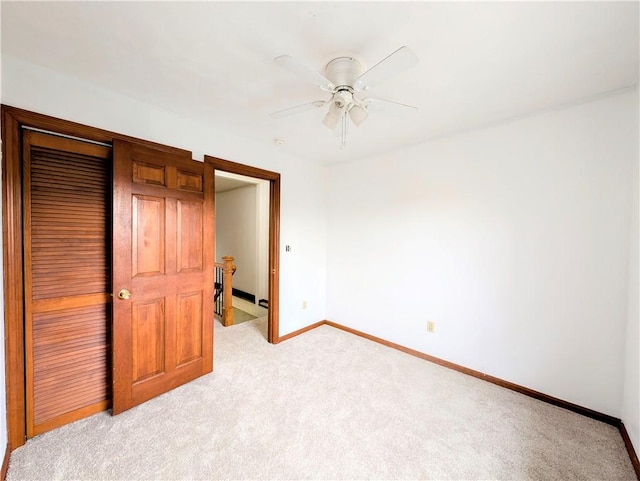 unfurnished bedroom featuring ceiling fan, light colored carpet, and a closet