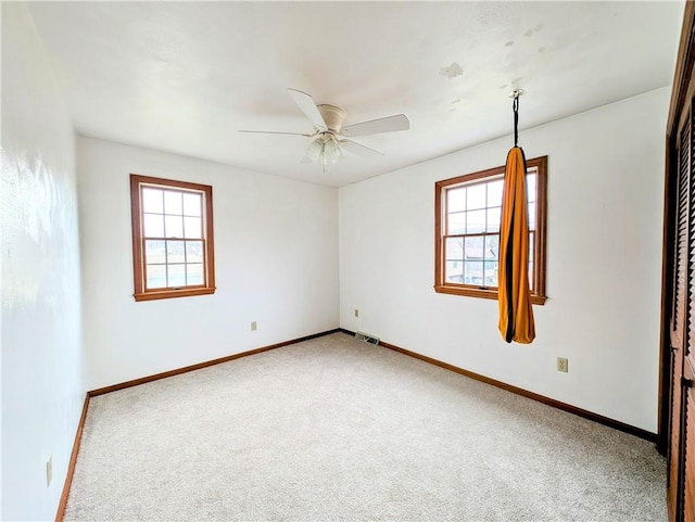 empty room with ceiling fan, carpet floors, and a wealth of natural light