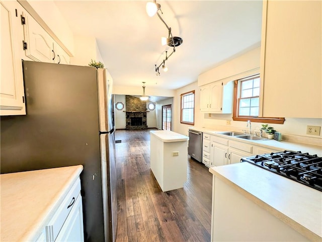 kitchen featuring appliances with stainless steel finishes, a fireplace, sink, and white cabinets