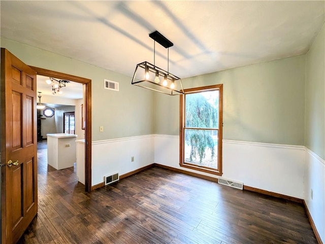 empty room featuring plenty of natural light and dark wood-type flooring