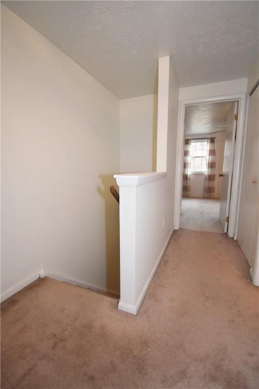 hall with light carpet and a textured ceiling