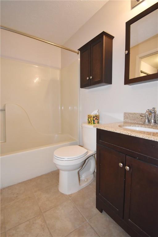 full bathroom with vanity, tile patterned floors, washtub / shower combination, and toilet