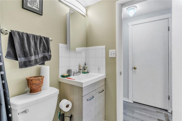 bathroom with vanity, toilet, wood-type flooring, and decorative backsplash