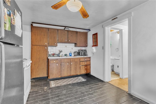 kitchen with ceiling fan, dark hardwood / wood-style floors, backsplash, and stainless steel refrigerator