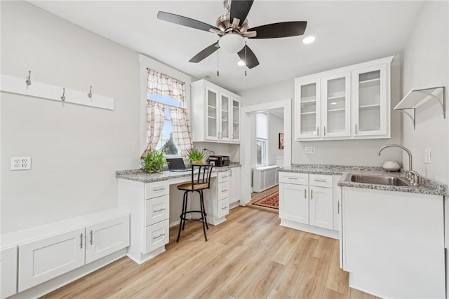 kitchen featuring white cabinetry, radiator, light wood-type flooring, a sink, and ceiling fan