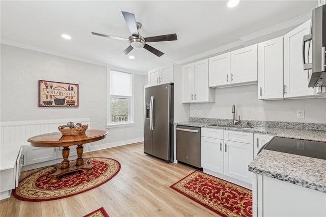 kitchen featuring a sink, a ceiling fan, appliances with stainless steel finishes, white cabinets, and light wood-style floors