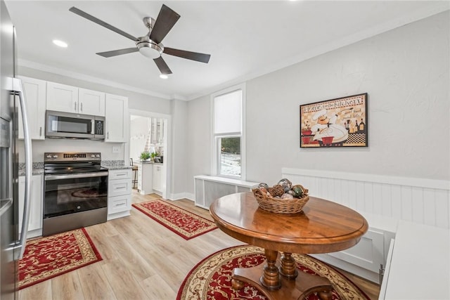 kitchen with ornamental molding, radiator, stainless steel appliances, and light wood-type flooring