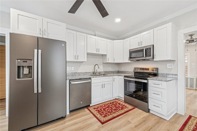 kitchen with a sink, light wood-type flooring, stainless steel appliances, white cabinets, and ceiling fan