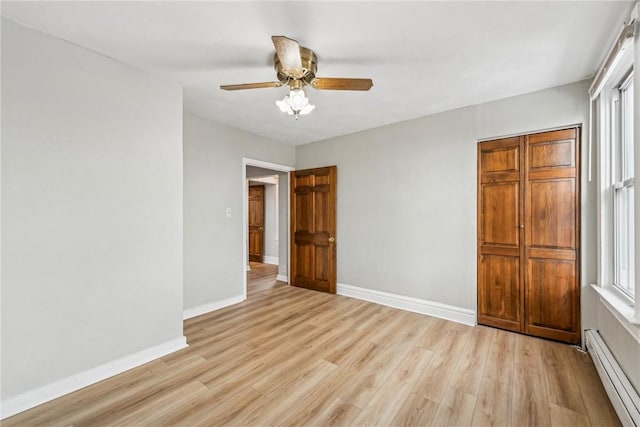 unfurnished bedroom featuring light wood finished floors, baseboards, a baseboard heating unit, and a ceiling fan