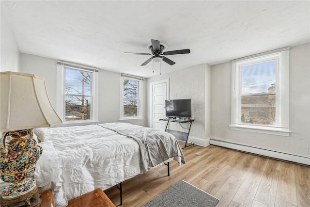 bedroom with baseboards, baseboard heating, light wood-type flooring, and a ceiling fan