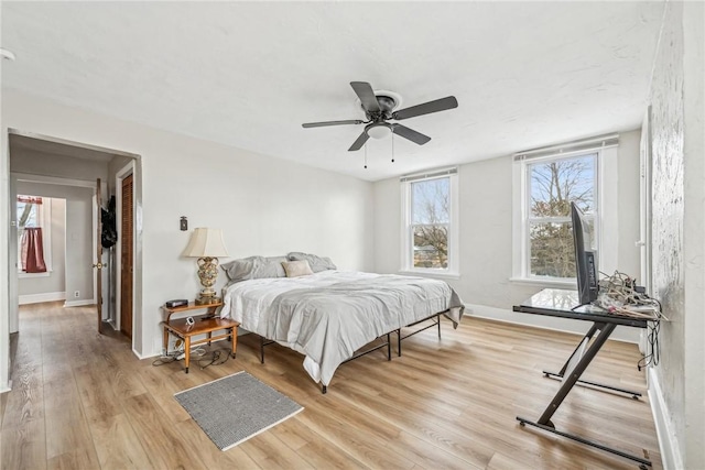 bedroom with light wood-style flooring, baseboards, and ceiling fan