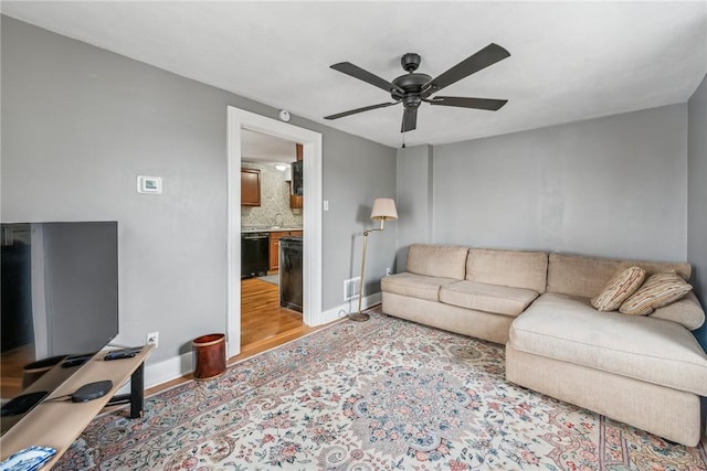 living room with baseboards, ceiling fan, visible vents, and light wood finished floors