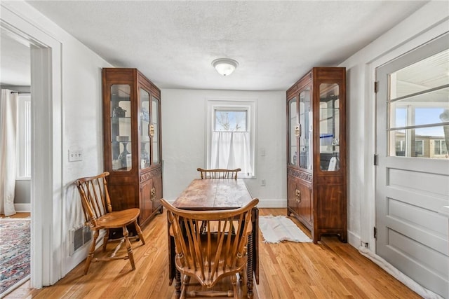 dining room with baseboards, visible vents, a textured ceiling, and light wood-style flooring