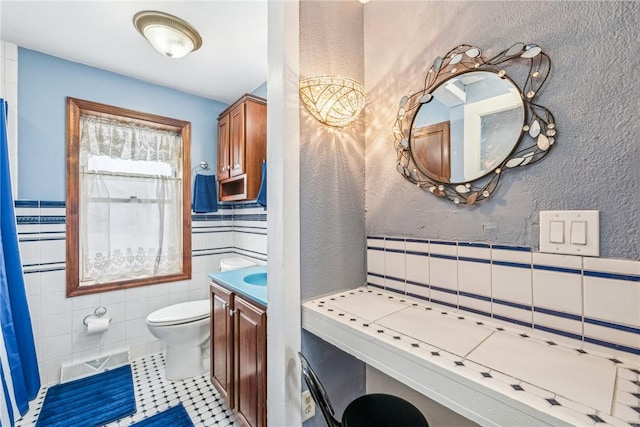 full bath featuring toilet, vanity, wainscoting, visible vents, and tile walls