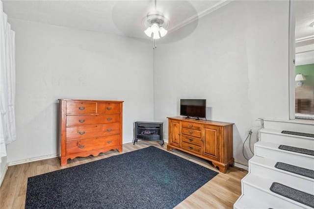 bedroom featuring ceiling fan, a wood stove, and light wood-type flooring
