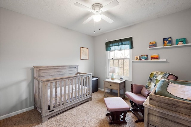 bedroom featuring a crib, carpet floors, a textured ceiling, and ceiling fan