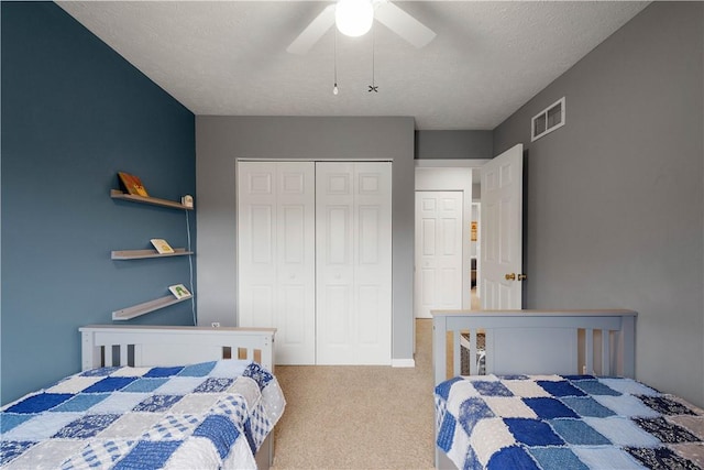 bedroom featuring ceiling fan, carpet flooring, a textured ceiling, and a closet