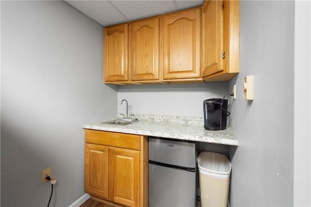 kitchen featuring sink, a drop ceiling, and stainless steel fridge