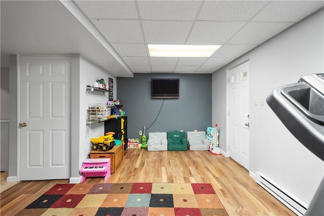 interior space with a baseboard heating unit, a paneled ceiling, and hardwood / wood-style floors