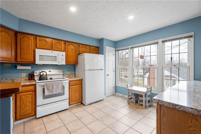 kitchen featuring white appliances, a textured ceiling, and light tile patterned floors