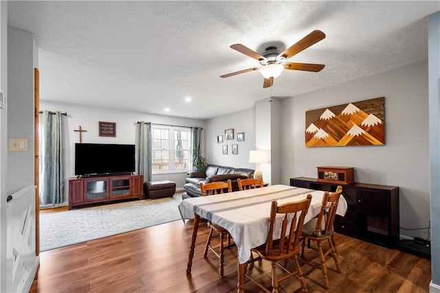 dining room with ceiling fan, dark wood-type flooring, and a textured ceiling