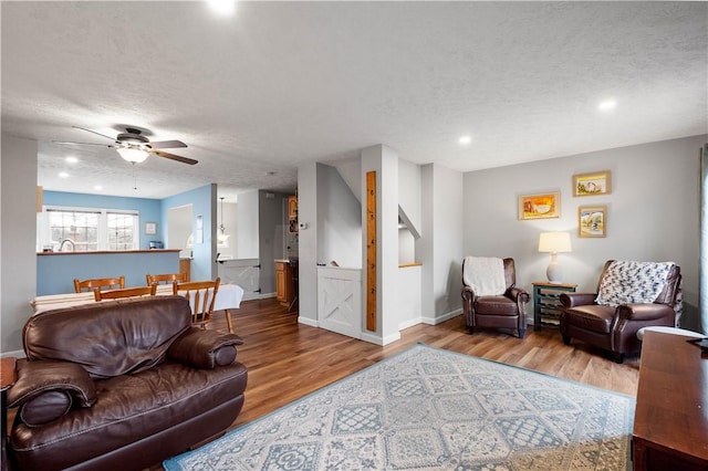 living room with hardwood / wood-style floors, a textured ceiling, and ceiling fan