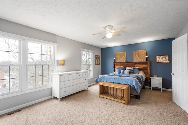 carpeted bedroom featuring ceiling fan and a textured ceiling