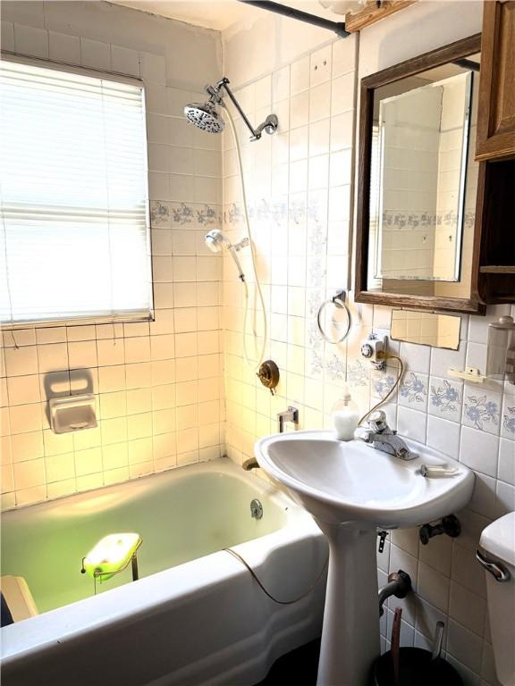 bathroom featuring decorative backsplash, tiled shower / bath, toilet, and tile walls