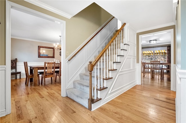 stairway with an inviting chandelier, hardwood / wood-style floors, and crown molding