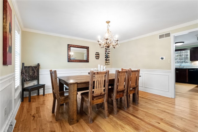 dining space with ornamental molding, sink, a chandelier, and light hardwood / wood-style floors