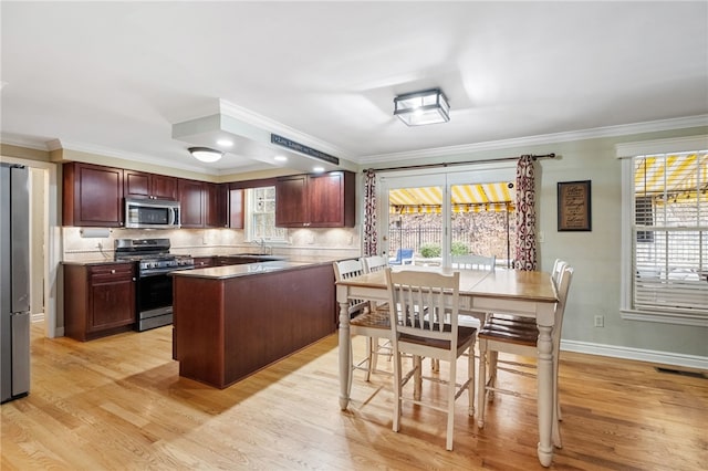 kitchen featuring crown molding, appliances with stainless steel finishes, light wood-type flooring, and decorative backsplash