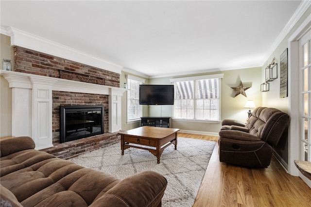 living room featuring ornamental molding, a brick fireplace, and light hardwood / wood-style floors