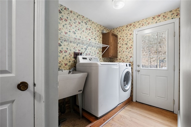 laundry area featuring washing machine and clothes dryer and light wood-type flooring