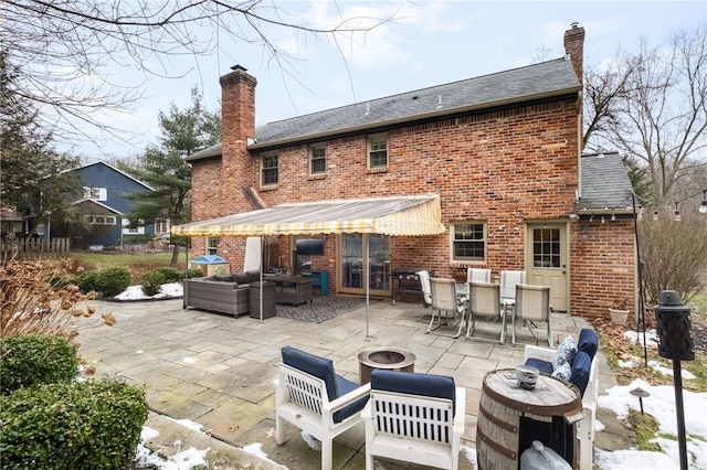 rear view of house with a patio area and an outdoor living space with a fire pit