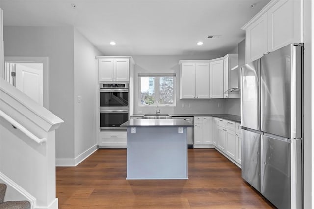 kitchen featuring dark wood-type flooring, appliances with stainless steel finishes, a kitchen island, and white cabinets