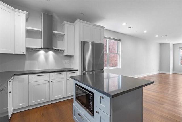 kitchen featuring white cabinetry, black microwave, stainless steel fridge, and wall chimney exhaust hood