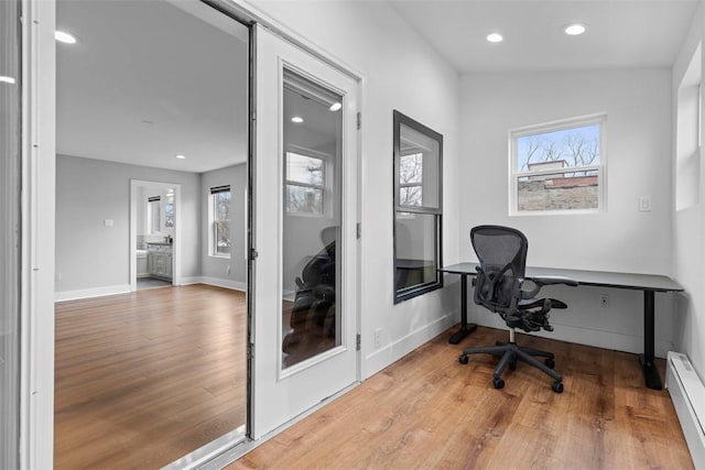 home office featuring light wood-type flooring and a baseboard heating unit