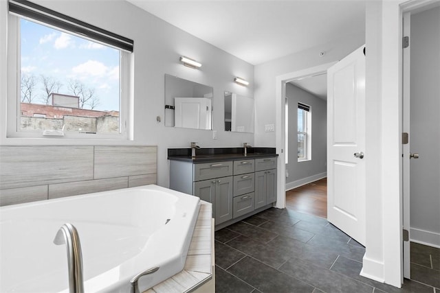 bathroom with a relaxing tiled tub, tile patterned floors, and vanity