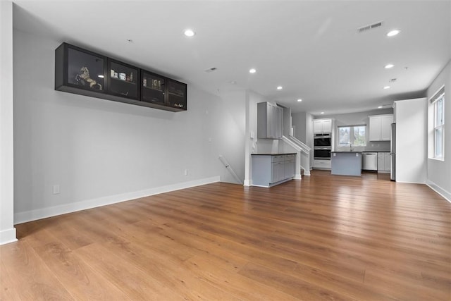 unfurnished living room featuring sink and light wood-type flooring