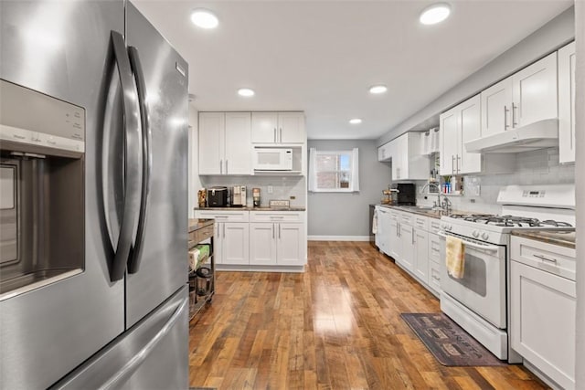 kitchen featuring white cabinetry, hardwood / wood-style floors, white appliances, and decorative backsplash