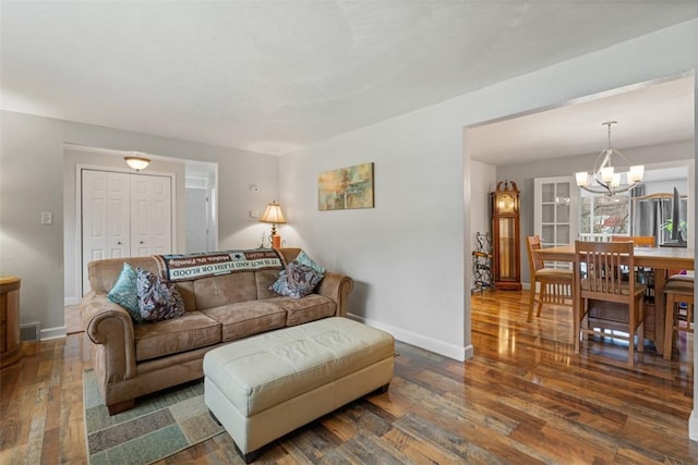 living room featuring dark wood-type flooring and an inviting chandelier